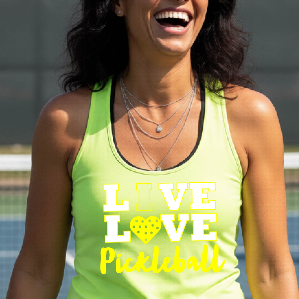 A woman on a pickleball court wearing a lime green tank top with a yellow and white graphic that reads 'LIVE LOVE Pickleball' with a heart shaped pickleball motiff replace the O.