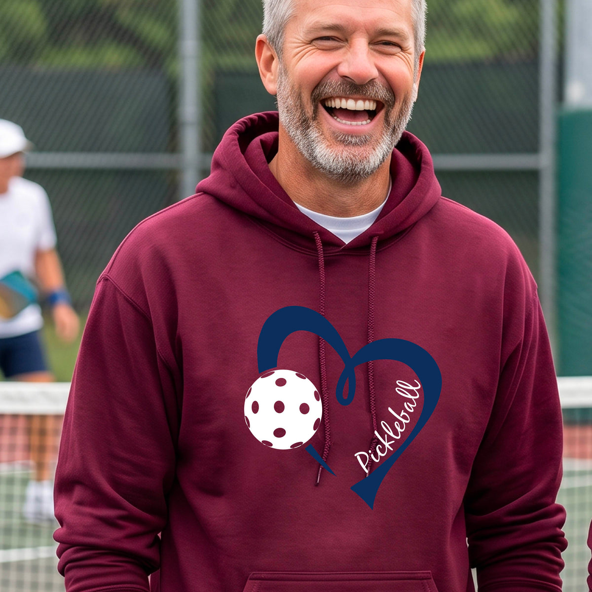A smiling man wearing a maroon pullover hoodie with a navy blue heart outline, a white pickleball graphic, and the word 'Pickleball' on the front.