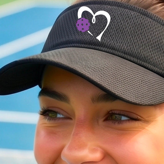 Close-up of a person wearing a black visor with a white heart outline and a purple pickleball graphic on the front.