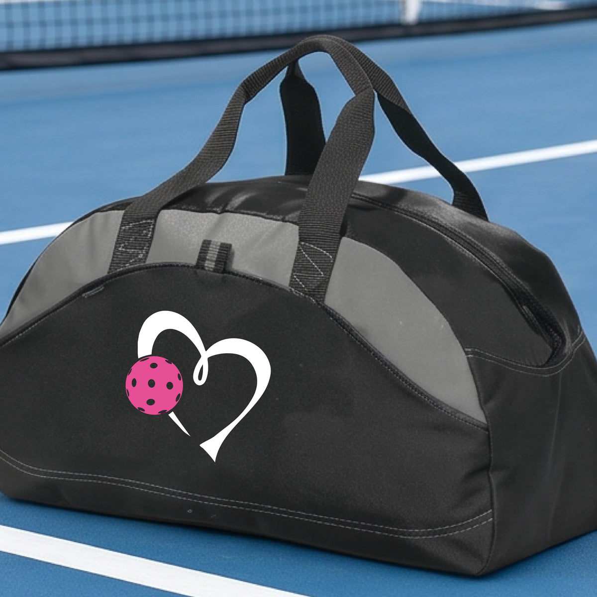 A black pickleball duffel bag with gray panels, featuring a white heart outline and a pink pickleball graphic on the front.