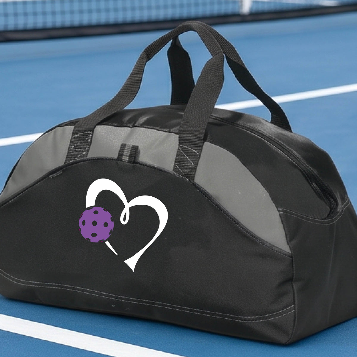 A black pickleball duffel bag with gray panels, featuring a white heart outline and a purple pickleball graphic on the front,.