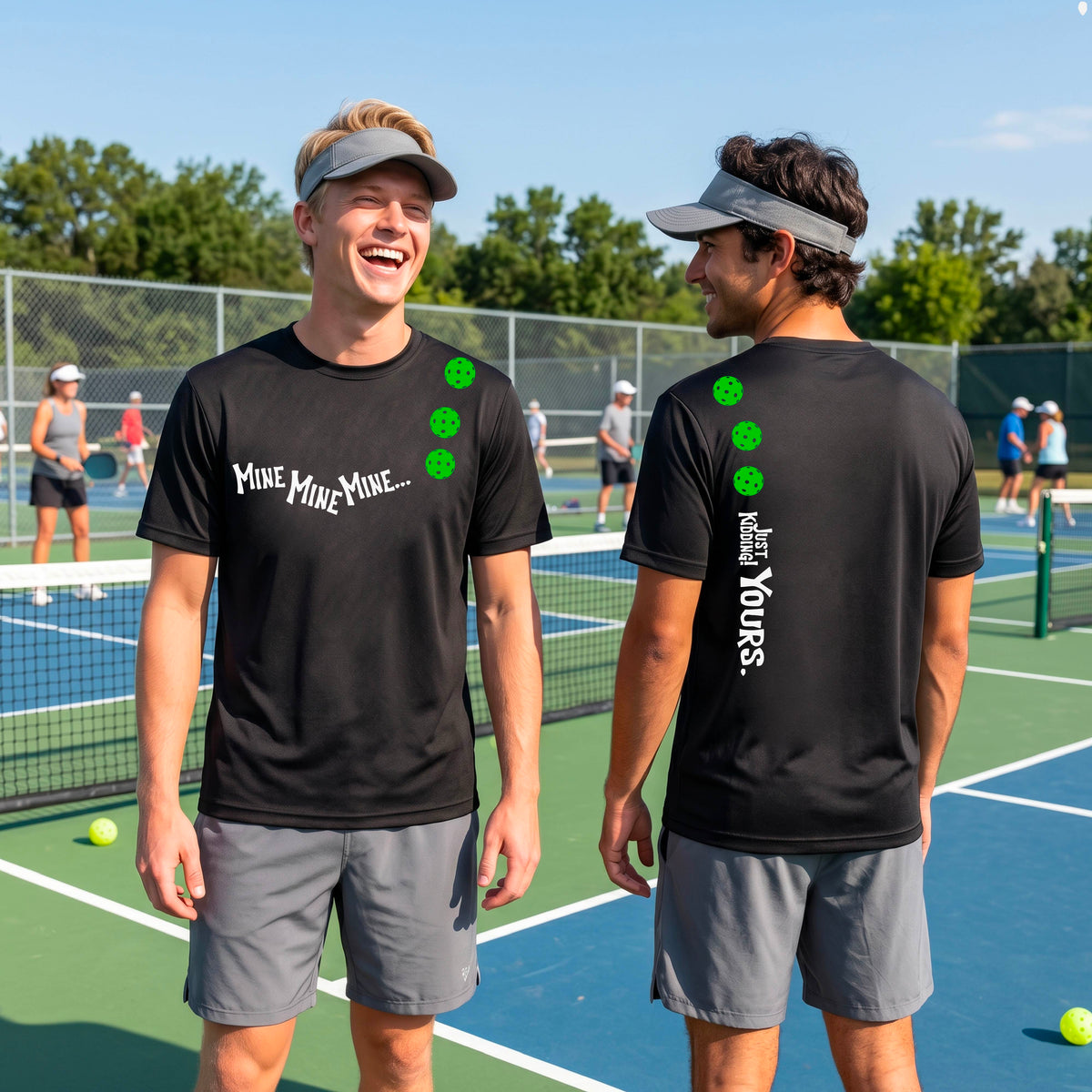 Two men on a pickleball court wearing matching black short-sleeve t-shirts. One shows the front with the text 'MINE MINE MINE' along with three pickleball graphics. and the back text 'JUST KIDDING YOURS, along with three pickleball graphics.
