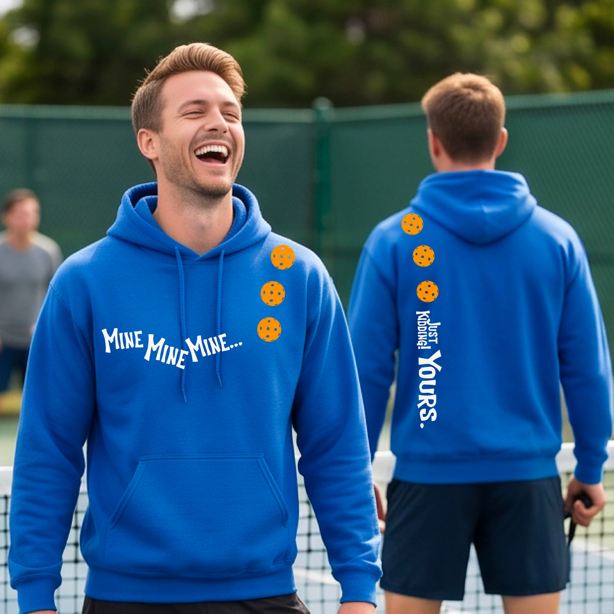 Two men on a pickleball court wearing matching royal blue unisex hoodie pullovers. One shows the front with the text 'MINE MINE MINE' along with three pickleball graphics. and the back text 'JUST KIDDING YOURS, along with three pickleball graphics.