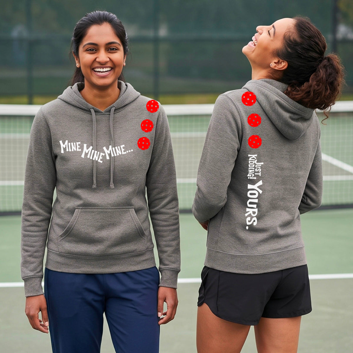 Two women on a pickleball court wearing matching gray fitted hoodie pullovers. One shows the front with the text 'MINE MINE MINE' along with three pickleball graphics. and the back text 'JUST KIDDING YOURS, along with three pickleball graphics.