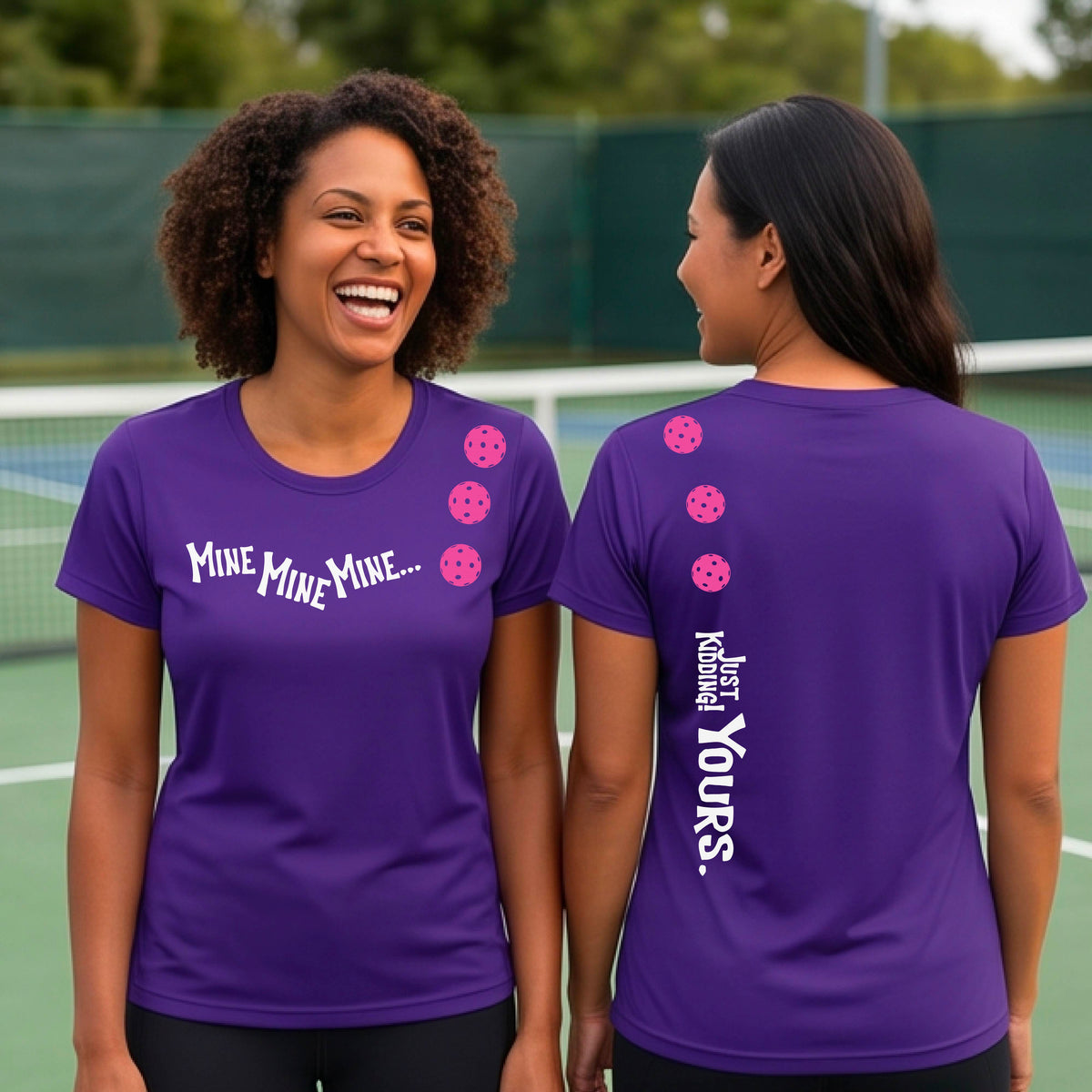 Two women on a pickleball court wearing matching purple short-sleeve atghletic t-shirts. One shows the front with the text 'MINE MINE MINE' along with three pickleball graphics. and the back text 'JUST KIDDING YOURS, along with three pickleball graphics.