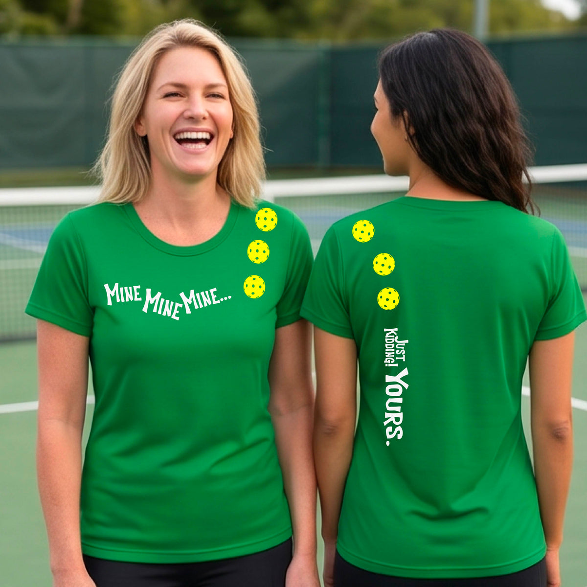 Two women on a pickleball court wearing matching green short-sleeve atghletic t-shirts. One shows the front with the text 'MINE MINE MINE' along with three pickleball graphics. and the back text 'JUST KIDDING YOURS, along with three pickleball graphics.