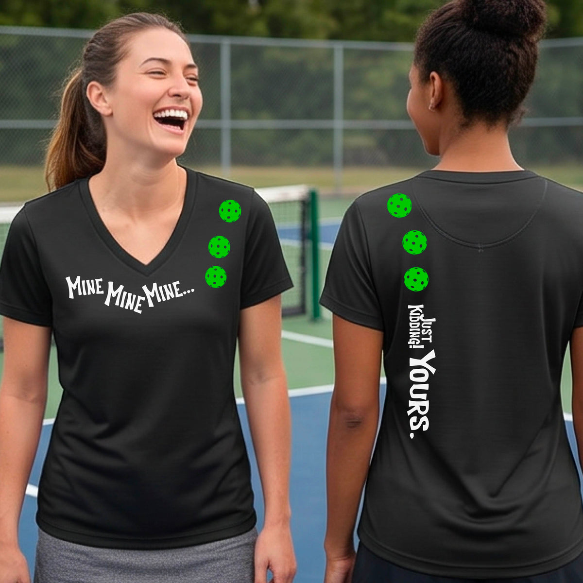 Two women on a pickleball court wearing matching black short-sleeve v-neck t-shirts.  One shows the front with the text 'MINE MINE MINE' along with three pickleball graphics. and the back text 'JUST KIDDING YOURS, along with three pickleball graphics.