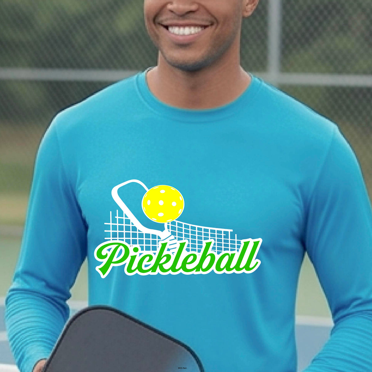 A woman wearing a bright blue long-sleeve t-shirt with a graphic on the front that has white and green text "PICKLEBALL'  with a white pickleball paddle and net and a yellow pickleball above the text graphic.