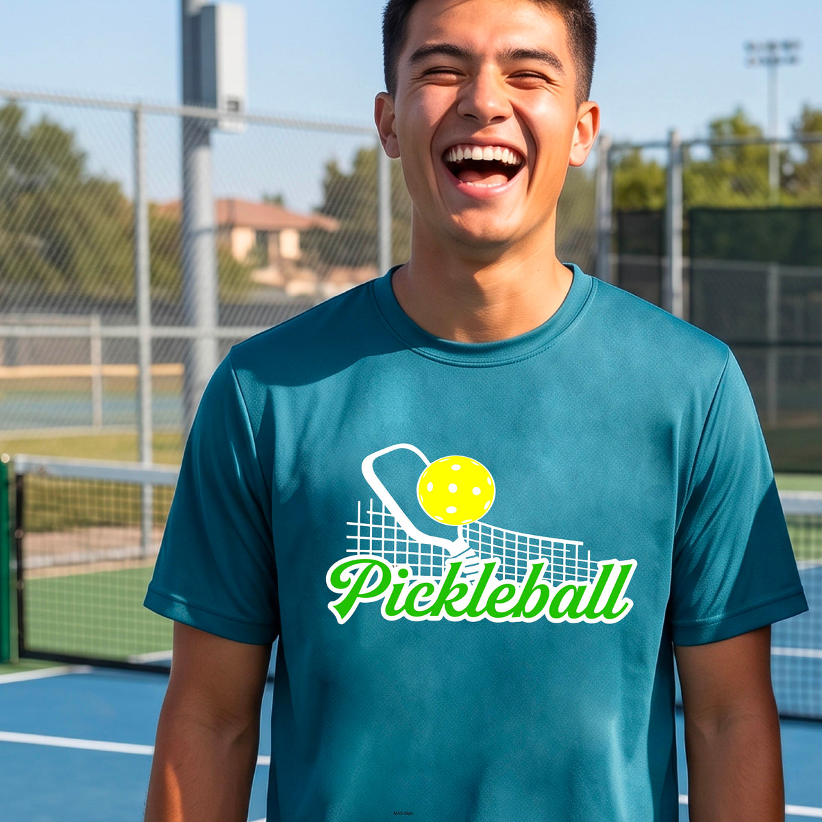 A man wearing a teal short-sleeve t-shirt with a graphic on the front that has white and green text "PICKLEBALL'  with a white pickleball paddle and net and a yellow pickleball above the text graphic.