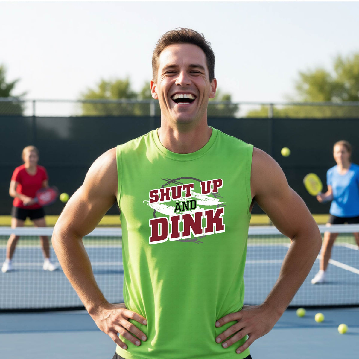 A man on a pickleball court wearing a lime green sleeveless t-shirt with a white, gray and black graphic of the text: ‘Shut Up and Dink, standing on a pickleball court.