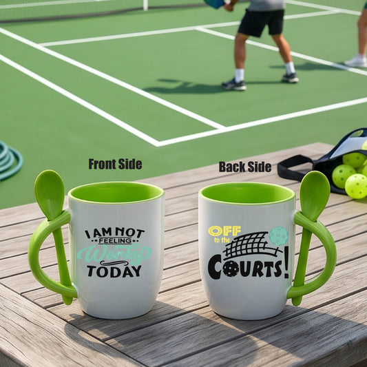 a white and green 12 ounce coffee mug with a built in spoon in the handle with and a fun pickleball graphic and the text “NOT FEELING WORKY TODAY OFF TO THE COURTS”