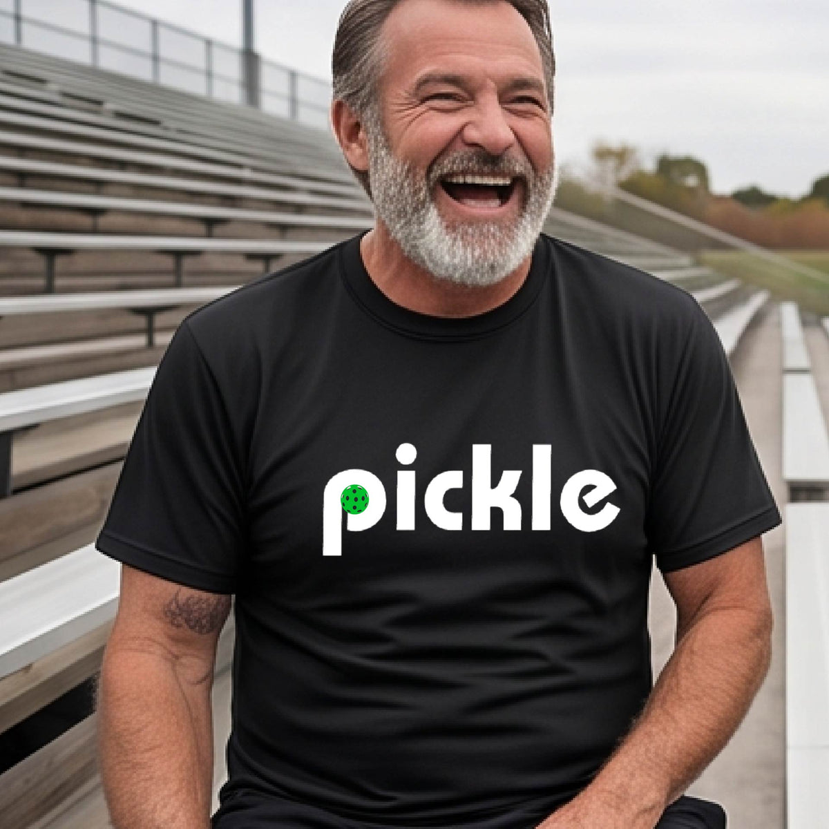 A man wearing a black long-sleeve t-shirt with a white graphic of ‘PICKLE’ with a green pickleball integrated into the letter P printed on the front.