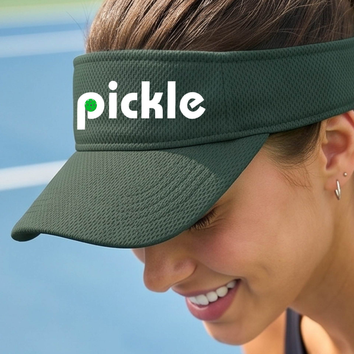 A close-up of a green pickleball visor with a white graphic of ‘PICKLE’ with a green pickleball integrated into the letter P, in front of a pickleball court. 