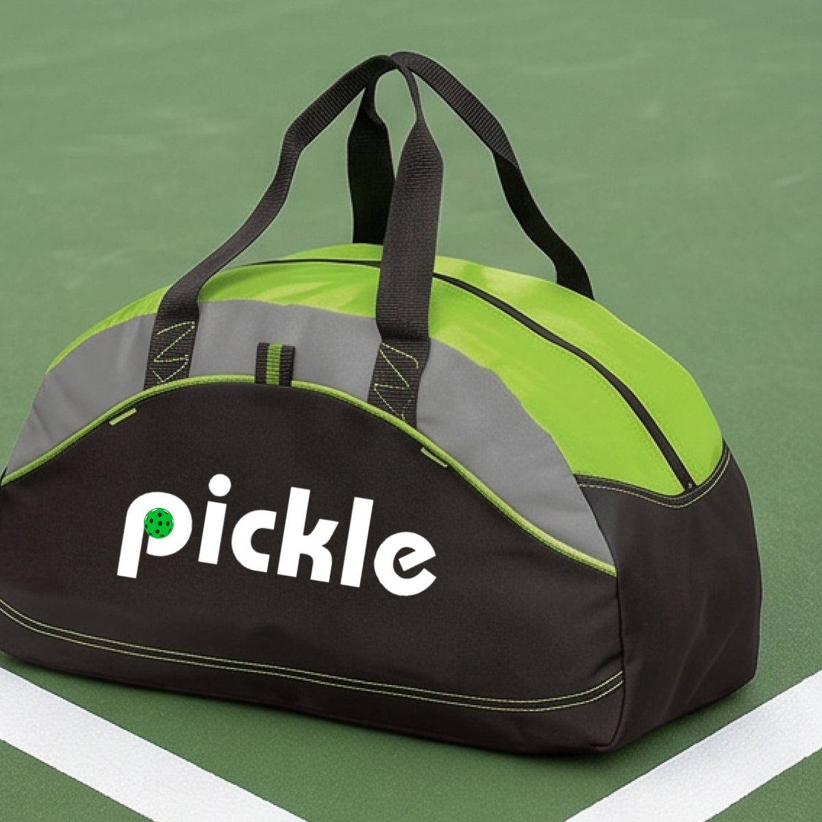 A lime green, black, and gray duffel bag with the white text  'pickle' printed in white on the front with a green pickleball in the center of hte letter P, placed on a outdoor pickleball court.