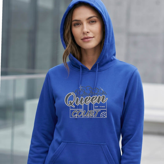 A woman wearing a royal blue unisex hoodie with a graphic print that reads 'Queen of the Court' and pickleball motiff in white and gray.