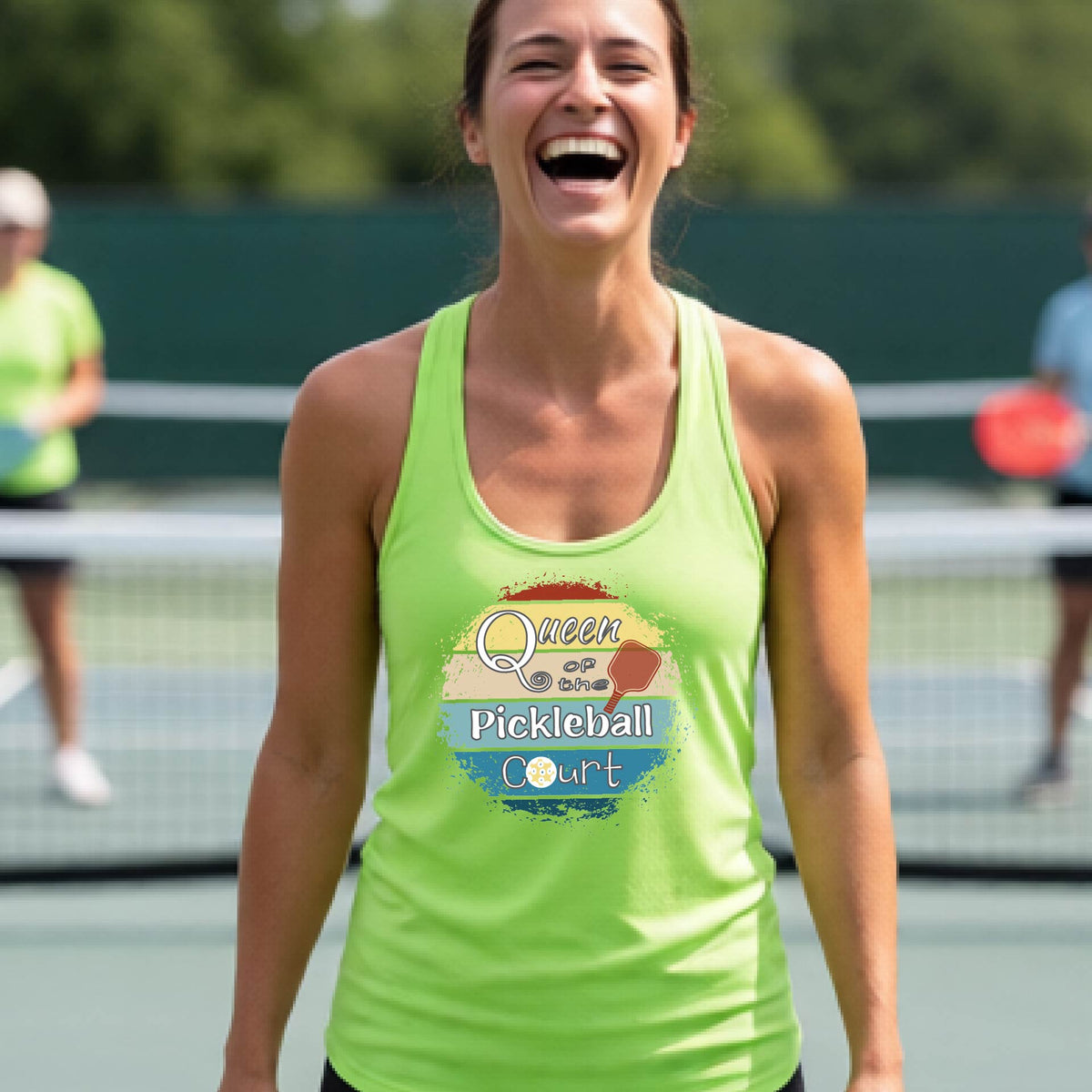 A woman laughing on a pickleball court, wearing a lime green racerback tank top with a retro-style graphic that reads 'Queen of the Pickleball Court' in a yellow, orange, and blue retro sunset design.