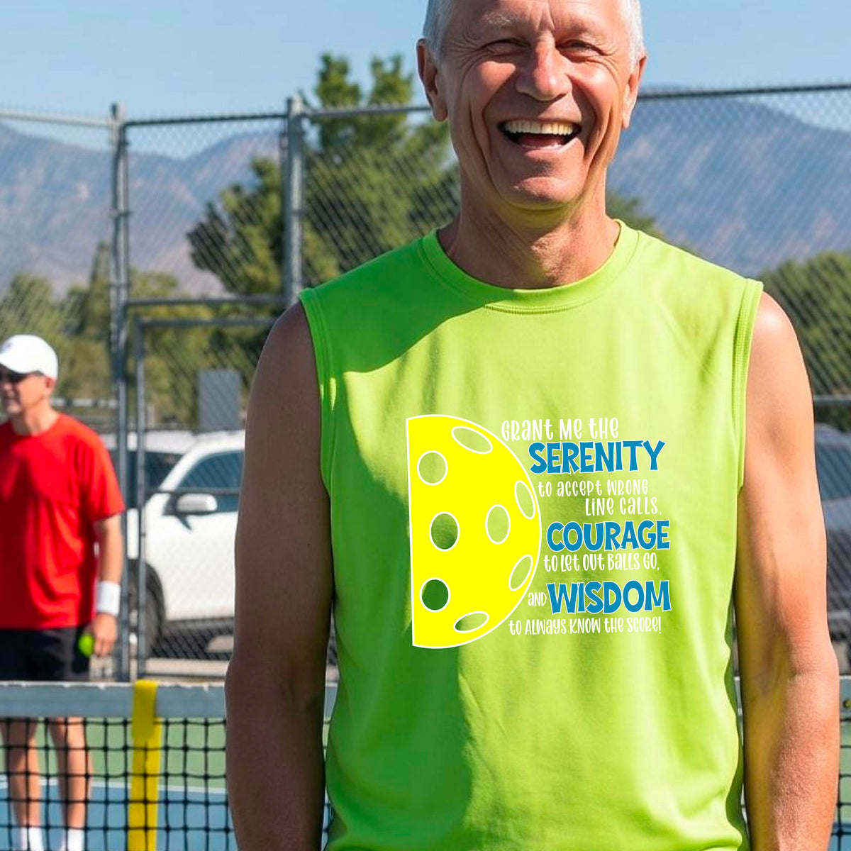 A man on a pickleball court wearing a lime green sleeveless t-shirt with a graphic of the Serenity Prayer made for pickleball:  “Grant me the serenity to Accept Wrong Line Calls; Courage to Let Out Balls Go; and, Wisdom to Always Know the Score” next to a half-pickleball icon, standing on a pickleball court.