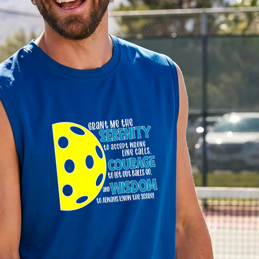 A man on a pickleball court wearing a royal blue sleeveless t-shirt with a graphic of the Serenity Prayer made for pickleball:  “Grant me the serenity to Accept Wrong Line Calls; Courage to Let Out Balls Go; and, Wisdom to Always Know the Score” next to a half-pickleball icon, standing on a pickleball court.