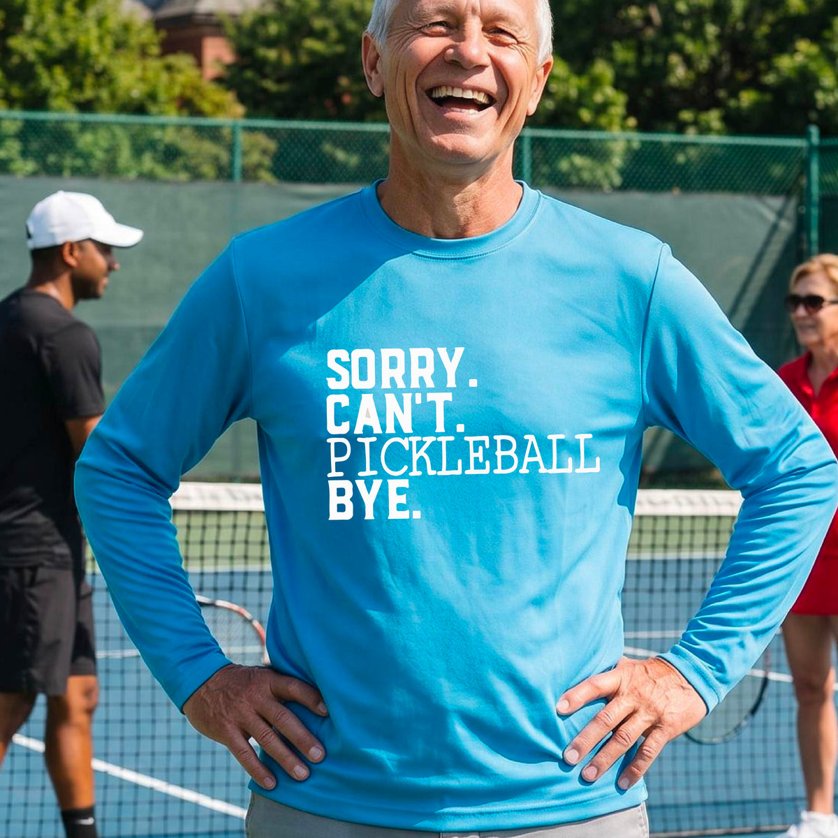 A man on a pickleball court wearing a bright blue long-sleeve t-shirt with a white graphic of the words  “SORRY. CAN’T. PICKLEBALL BYE” each on a separate line, on the front of the shirt. 