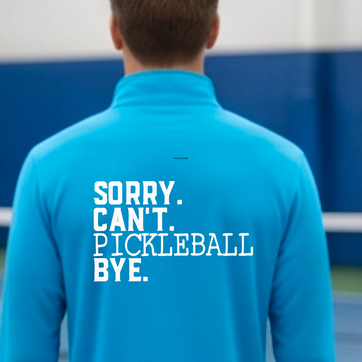 A man viewed from behind on a pickleball court wearing a bright blue quarter-zip shirt with a white graphic of the words  “SORRY. CAN’T. PICKLEBALL BYE” each on a separate line, on the front of the shirt.