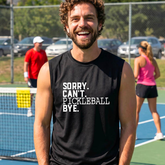 A man on a pickleball court wearing a black sleeveless t-shirt with a white graphic of the words  “SORRY. CAN’T. PICKLEBALL BYE” each on a separate line, on the front of the shirt. 
