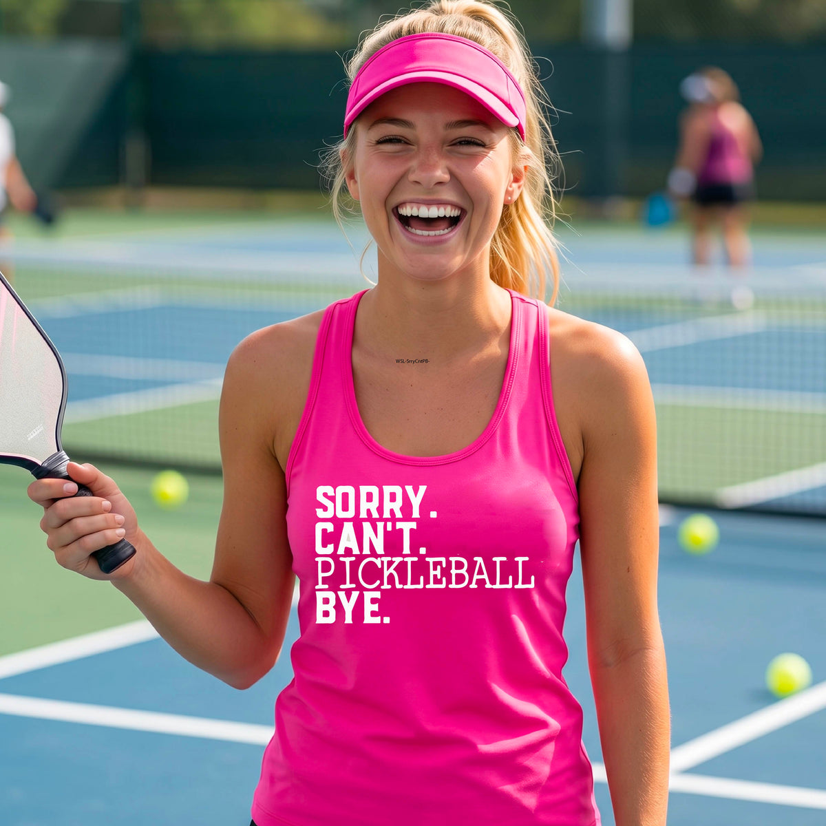 A woman on a pickleball court wearing a pink racerback tank top with a white graphic of the words  “SORRY. CAN’T. PICKLEBALL BYE” each on a separate line, on the fron of the shirt. 