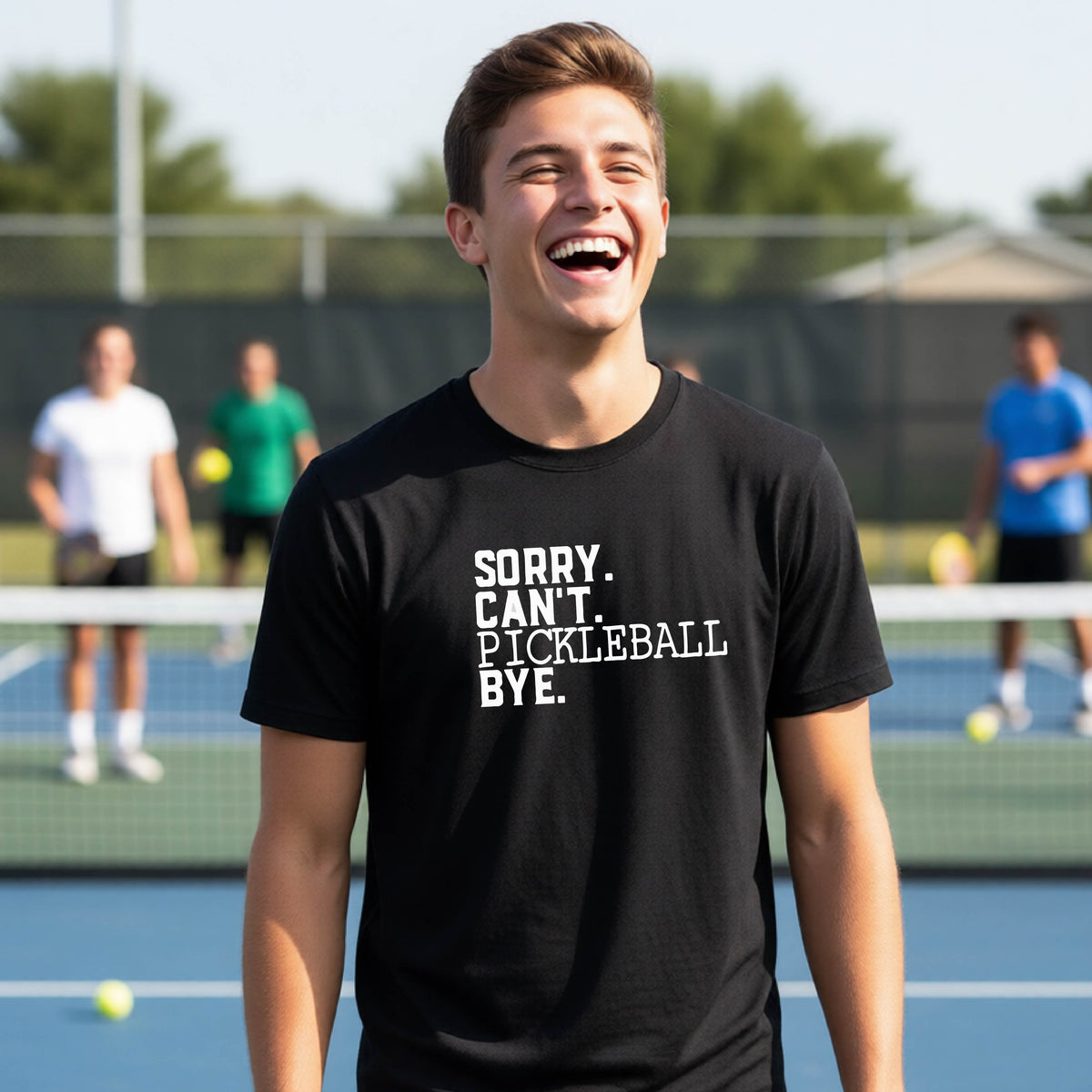 A young person on a pickleball court wearing a black short-sleeve t-shirt with a white graphic of the words  “SORRY. CAN’T. PICKLEBALL BYE” each on a separate line, on the front of the shirt. 
