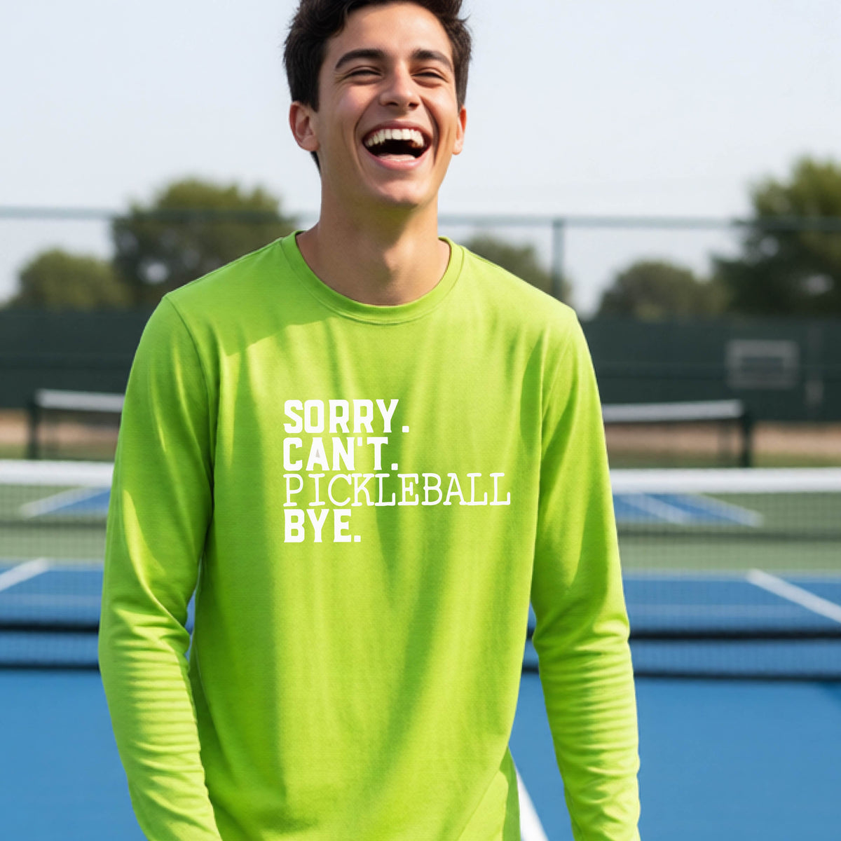 A young person on a pickleball court wearing a lime green short-sleeve t-shirt with a white graphic of the words  “SORRY. CAN’T. PICKLEBALL BYE” each on a separate line, on the front of the shirt.