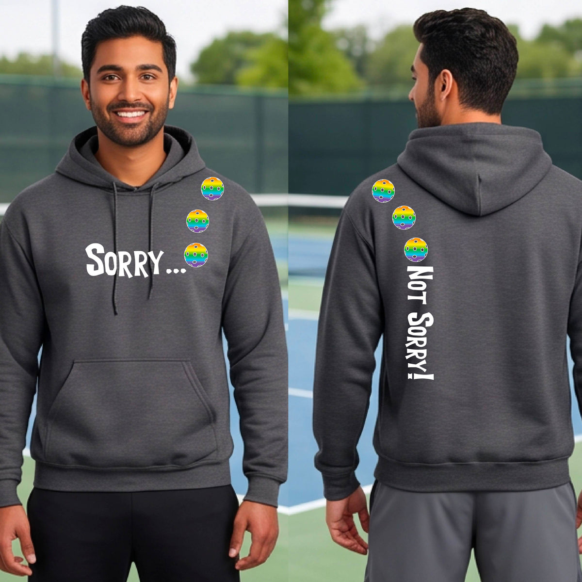 Two men on a pickleball court wearing unisex gray pullover hoodies with a front/back graphic design.  The front features the playful word “SORRY…” in bold white lettering, accented with three colorful pickleballs arranged diagonally across the upper chest.  The back design features “NOT SORRY!” in bold white lettering running vertically down the upper back, with three matching colorful pickleballs positioned above lettering.  