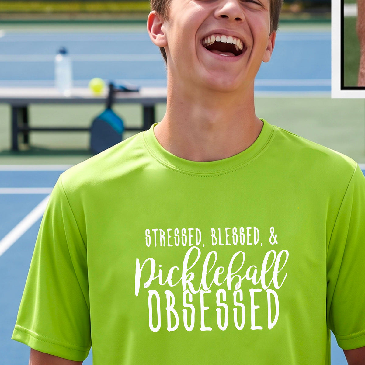 A man on a pickleball court wearing a lime green short-sleeve t-shirt with a white graphic of the words “Stressed, Blessed & Pickleball Obsessed” on the front of the shirt.