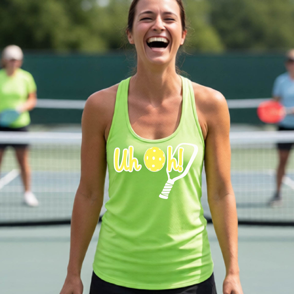 A woman on a pickleball court wearing a lime green racer-back tank top with a white and yellow graphic of the words “Uh Oh!” with a yellow pickleball replacing the letter O over the top of a pickleball paddle, on the front of the hoodie.