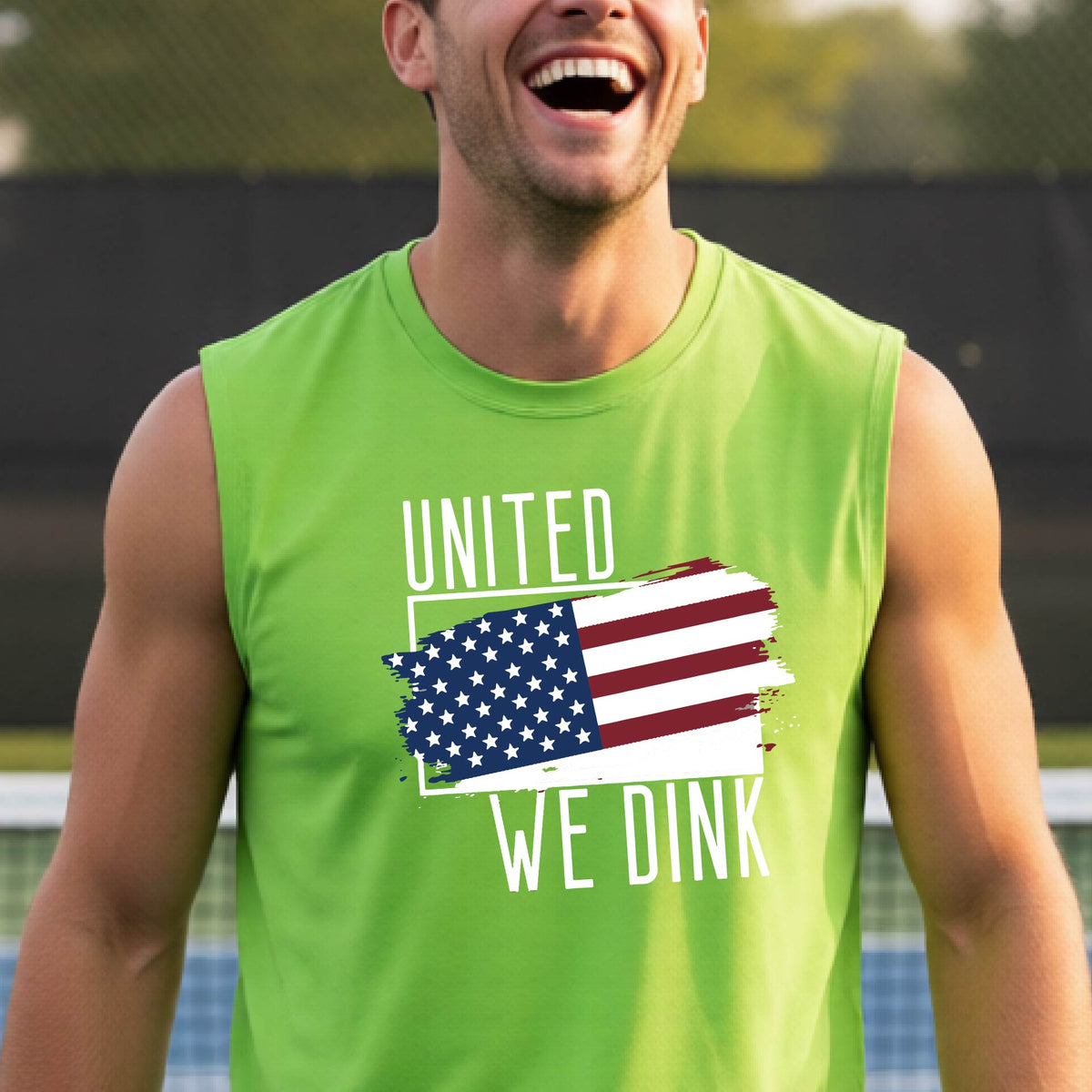 A man on a pickleball court wearing a lime green sleeveless t-shirt with a pickleball themed red, white and blue graphic of a patriotic flag with white words “UNITED WE DINK” above and below the flag on the front of the shirt.