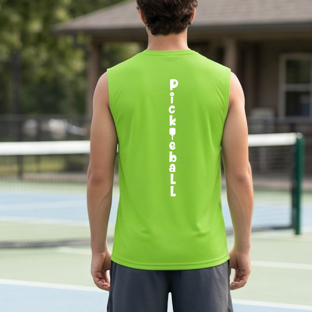 A man wearing a lime green sleeveless t-shirt with a white graphic text 'PICKLEBALL' on the back with a pickleball paddle replacing the L, standing on a pickleball court