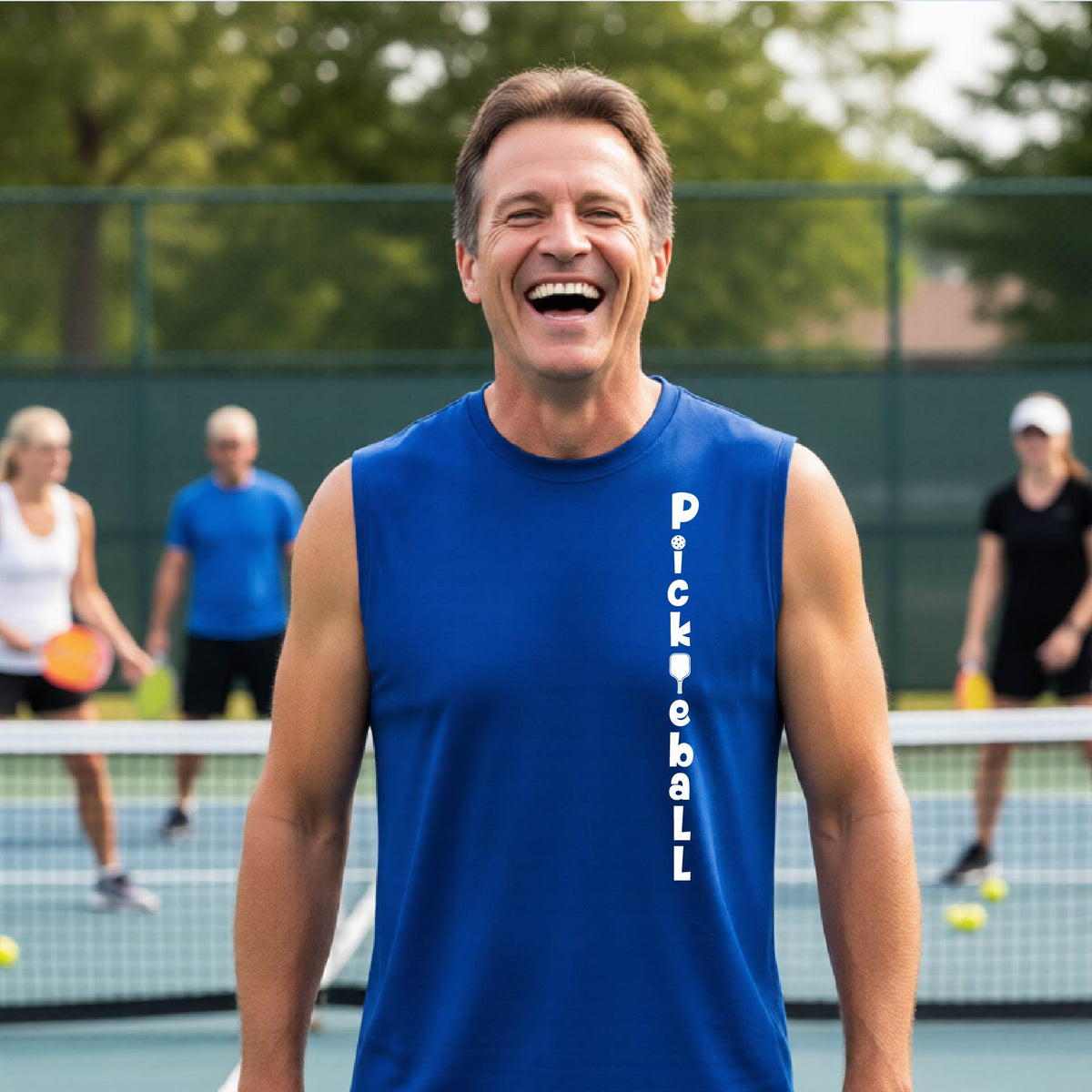 A man wearing a royal blue sleeveless t-shirt with a white graphic text 'PICKLEBALL' on the front with a pickleball paddle replacing the L, standing on a pickleball court