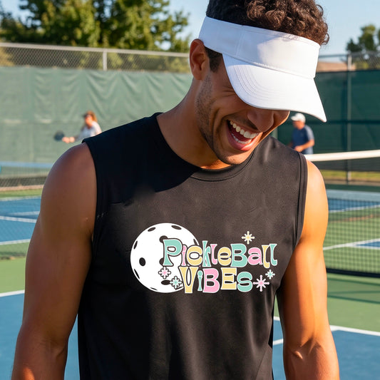 A close-up of a man on a pickleball wearing a black sleeveless t-shirt, with a colorful retro style font 'Pickleball Vibes' on top of a white pickleball graphic, on the front of the shirt.