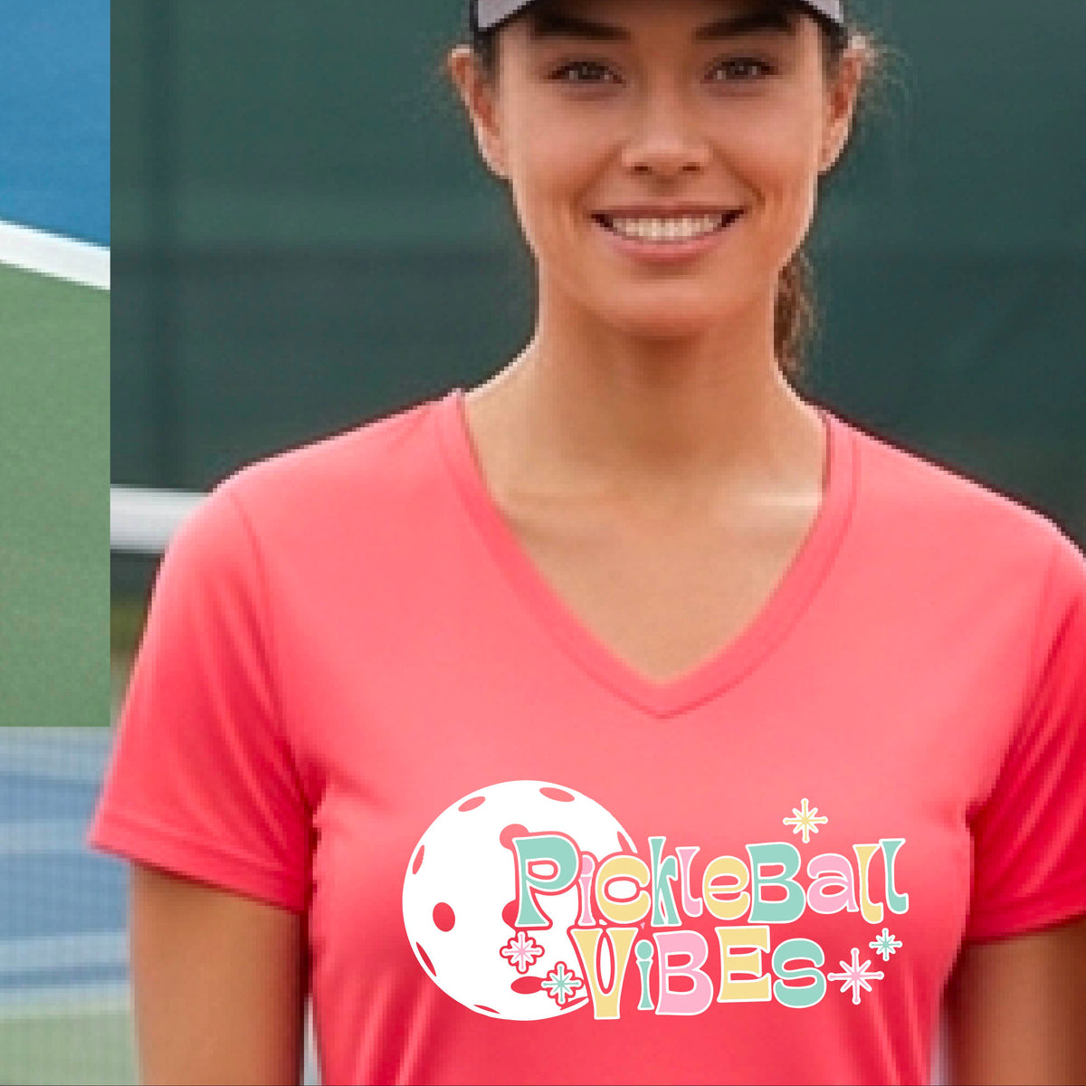 A close-up of a woman on a pickleball wearing a coral pink short-sleeve t-shirt, with a colorful retro style font 'Pickleball Vibes' on top of a white pickleball graphic, on the front of the shirt.