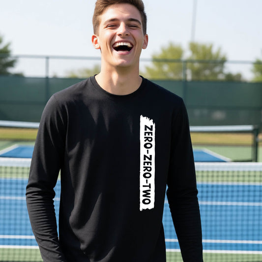 A close-up of a young person on a pickleball wearing a black short-sleeve t-shirt, , with a white graphic of artistic banner with the cutout words of ‘ZERO ZERO TWO’ , on the front of the shirt. 