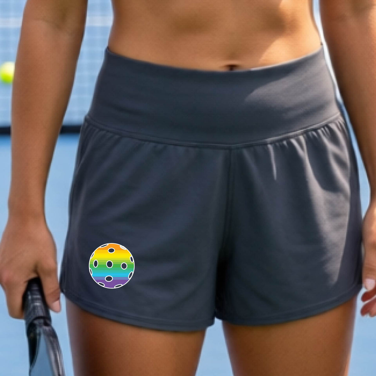 Gray athletic shorts with side pockets, shown on a model on a pickleball court. The shorts feature a colorful pickleball graphic on the left thigh.