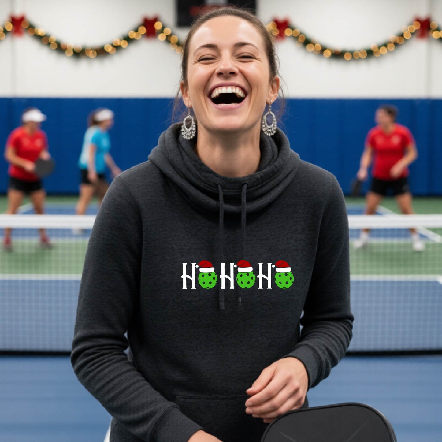 A black cowl-neck hooded sweatshirt featuring a graphic print that reads "Ho Ho Ho'" in white text. The design includes pickleball replacing the O in the text.