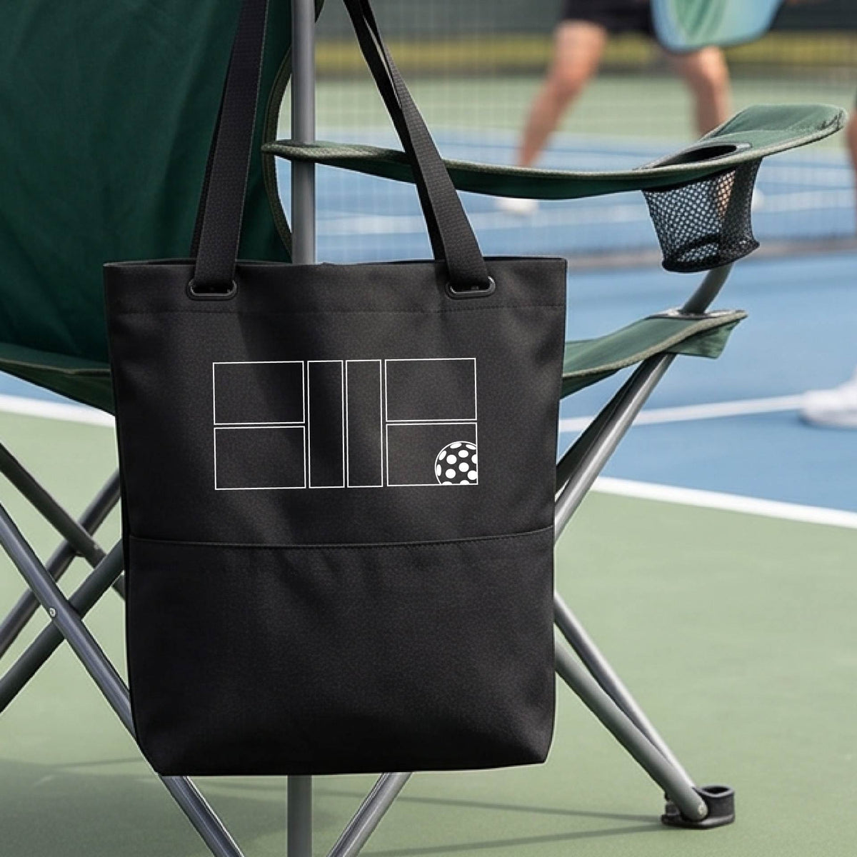 A close-up of a black medium size tote bag with a white pickleball geometric graphic of court and pickleball.