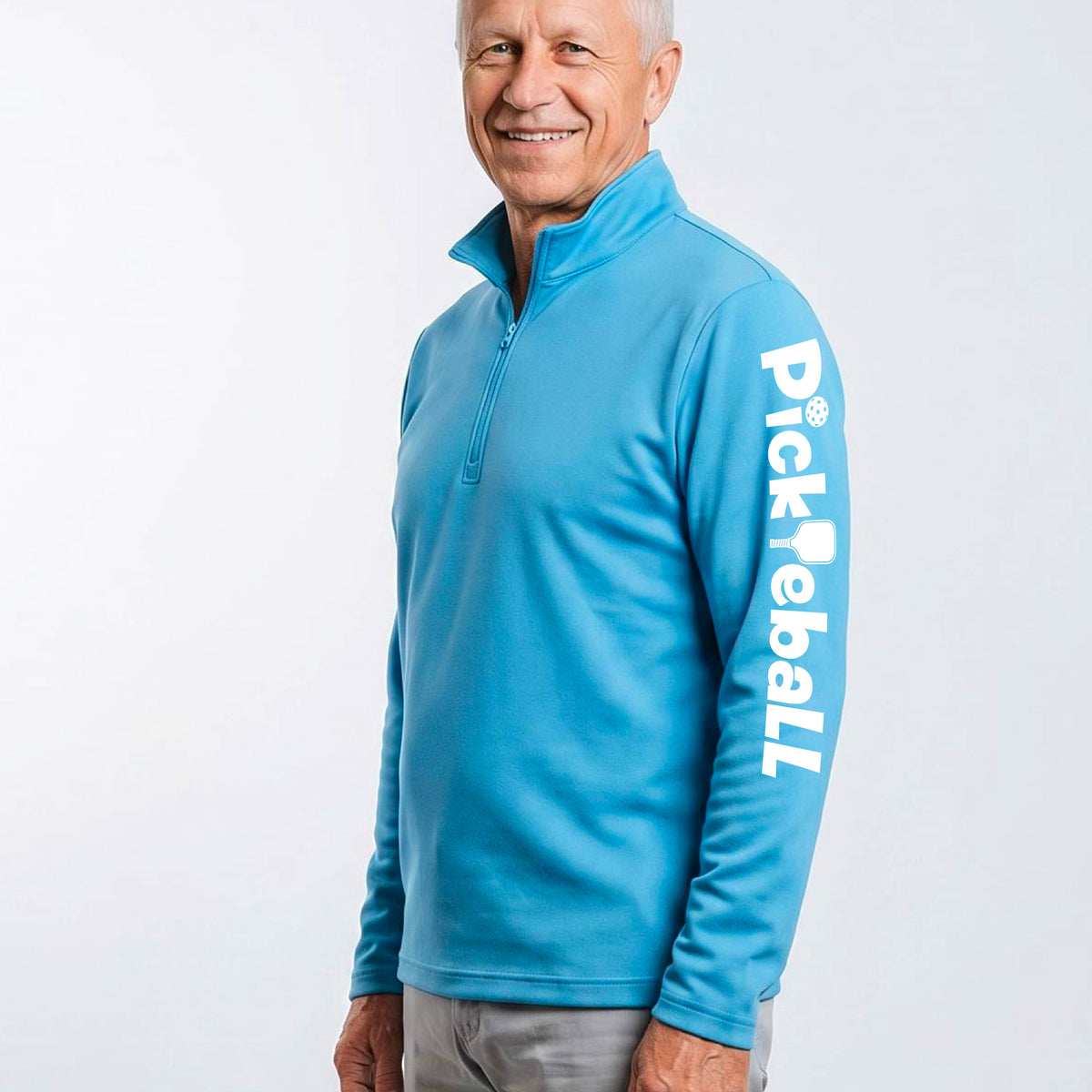 A man wearing a royal blue quarter-zip shirt with a white graphic text 'PICKLEBALL' with a pickleball paddle replacing the L, on the sleeve.