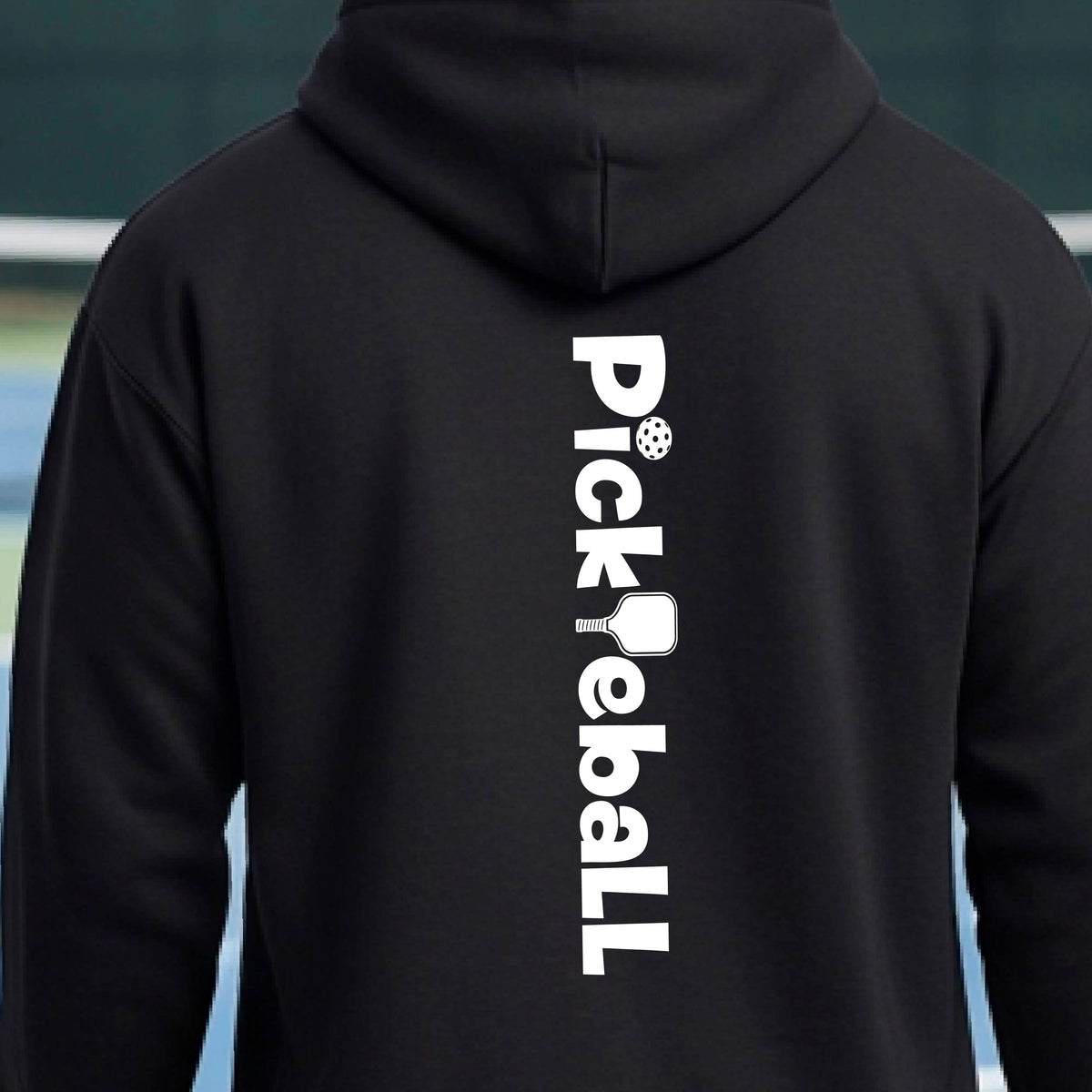 A person wearing a black hoodie, shown from the back. The hoodie features the word 'Pickleball' stacked vertically in white, with a pickleball graphic replacing the 'i' and 'ball' at the bottom.