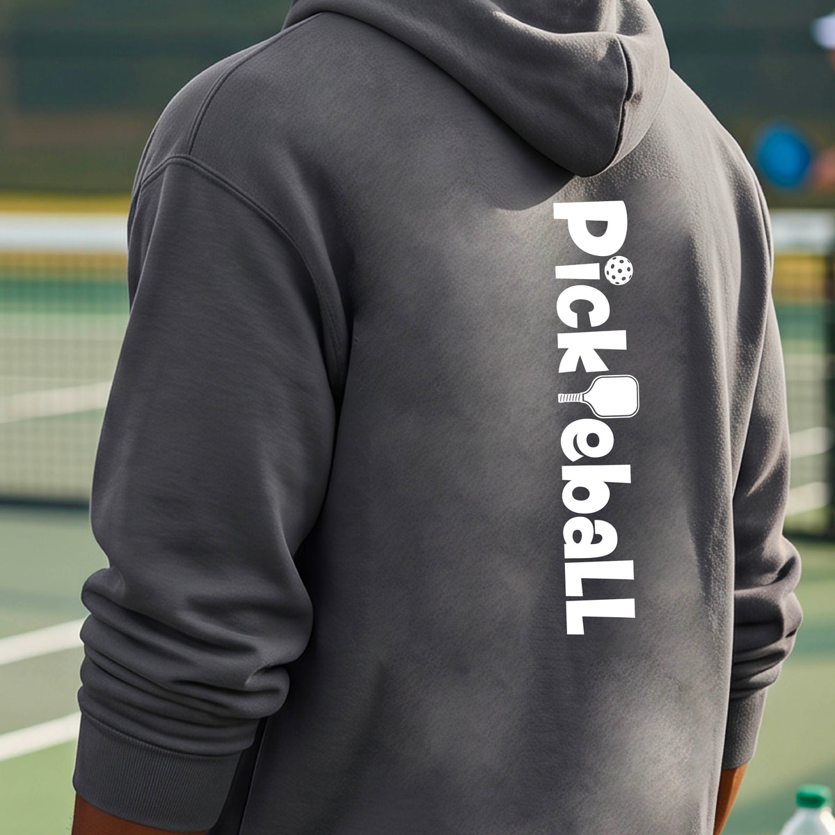 A person wearing a dark gray hoodie on a tennis court, shown from the back. The hoodie features the word 'Pickleball' printed vertically in white, with pickleball-themed icons replacing the letters 'i', 'k', and 'l'.