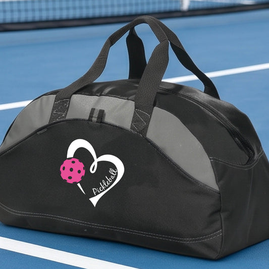 A closeup of a black and gray paneled duffel bag with a pickleball graphic of a white heart with a pickleball icon and the word 'Pickleball' in white script.