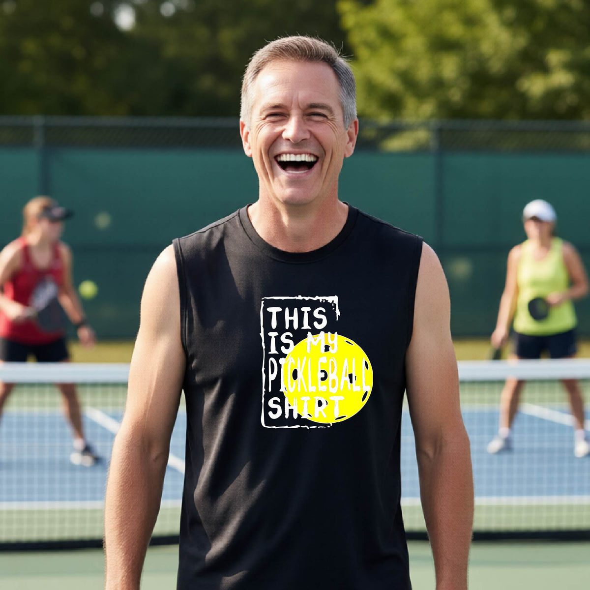 A man on a pickleball court wearing a black sleeveless shirt with a yellow and white graphic that reads 'THIS IS MY PICKLEBALL SHIRT' and a yellow pickleball icon.
