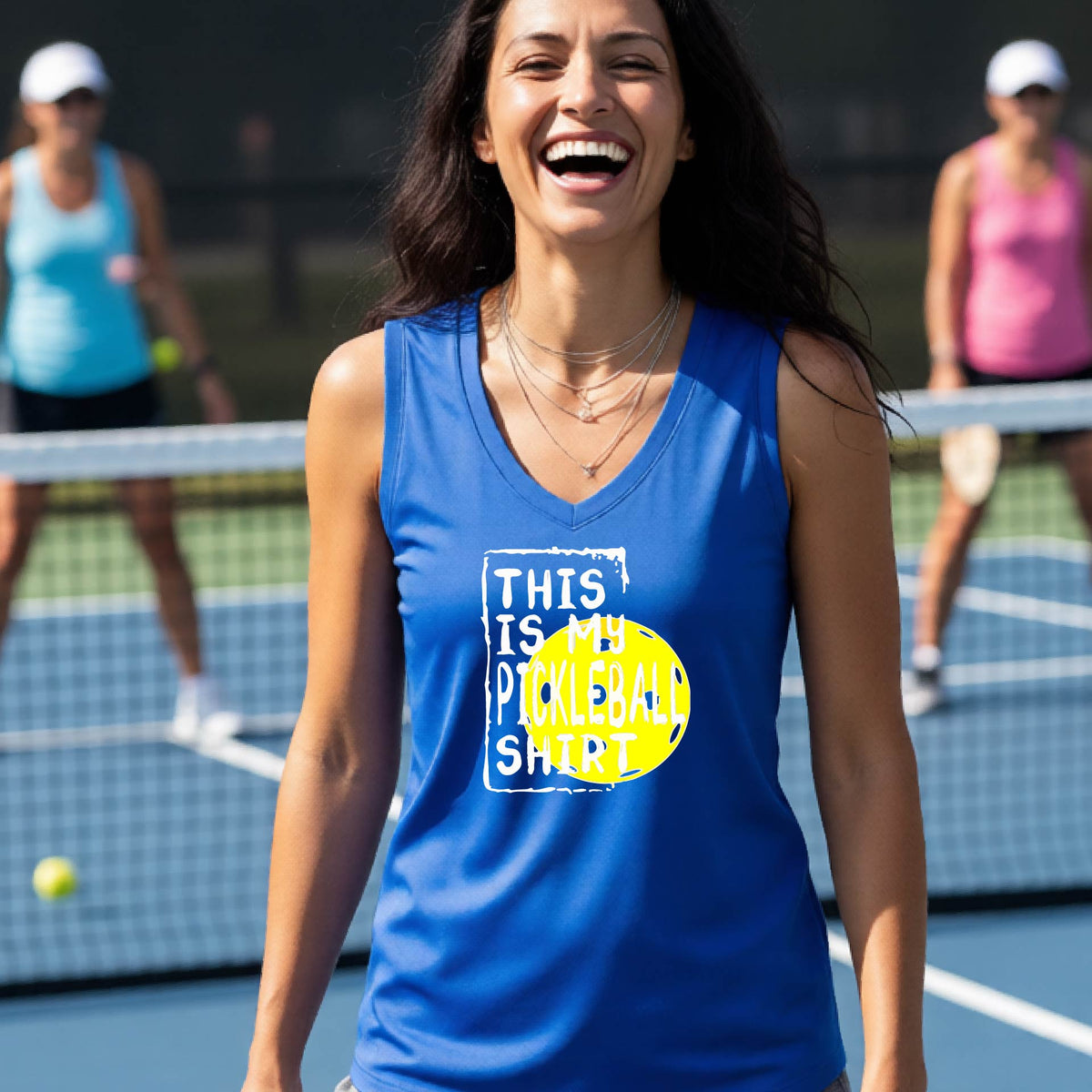 A woman on a pickleball court wearing a royal blue tank top with a yellow and white graphic that reads 'THIS IS MY PICKLEBALL SHIRT' including the yellow pickleball icon.