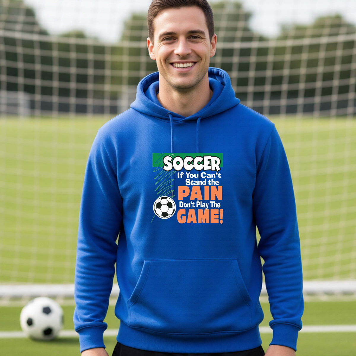 A smiling man on a soccer field while wearing a royal blue hoodie pullover with the graphic slogan 'SOCCER If You Can't Stand the PAIN Don't Play The GAME!' in green, white, and orange text.