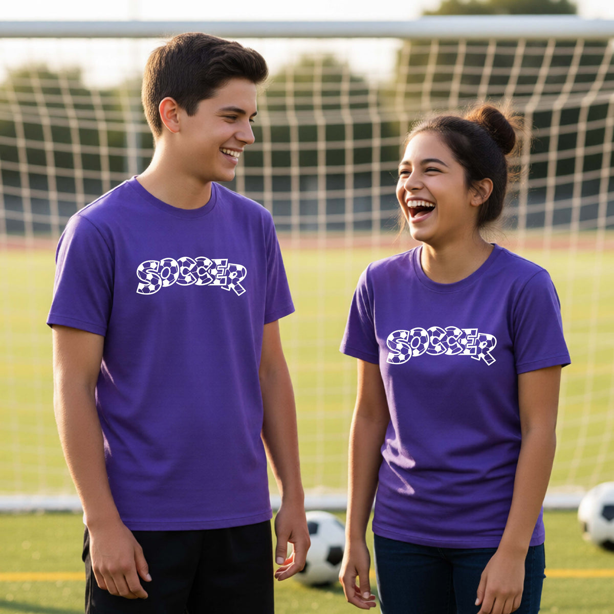 Two young athletics wearing matching purple t-shirt, standing on a soccer field in front of a goal net. with a white graphic of the word 'SOCCER' in a stylish soccer pattern printed on the chests.