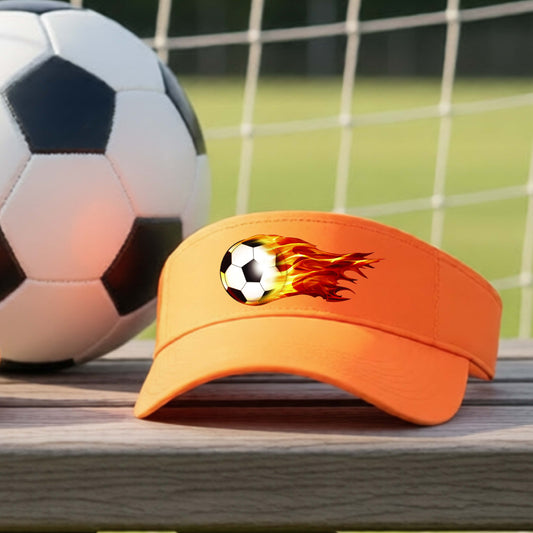 A close-up of an orange visor sitting on an outdoor bench next to a soccer ball with a white graphic of a soccer ball shooting through air and trailing yellow, red and orange flames behind it, printed on the front.