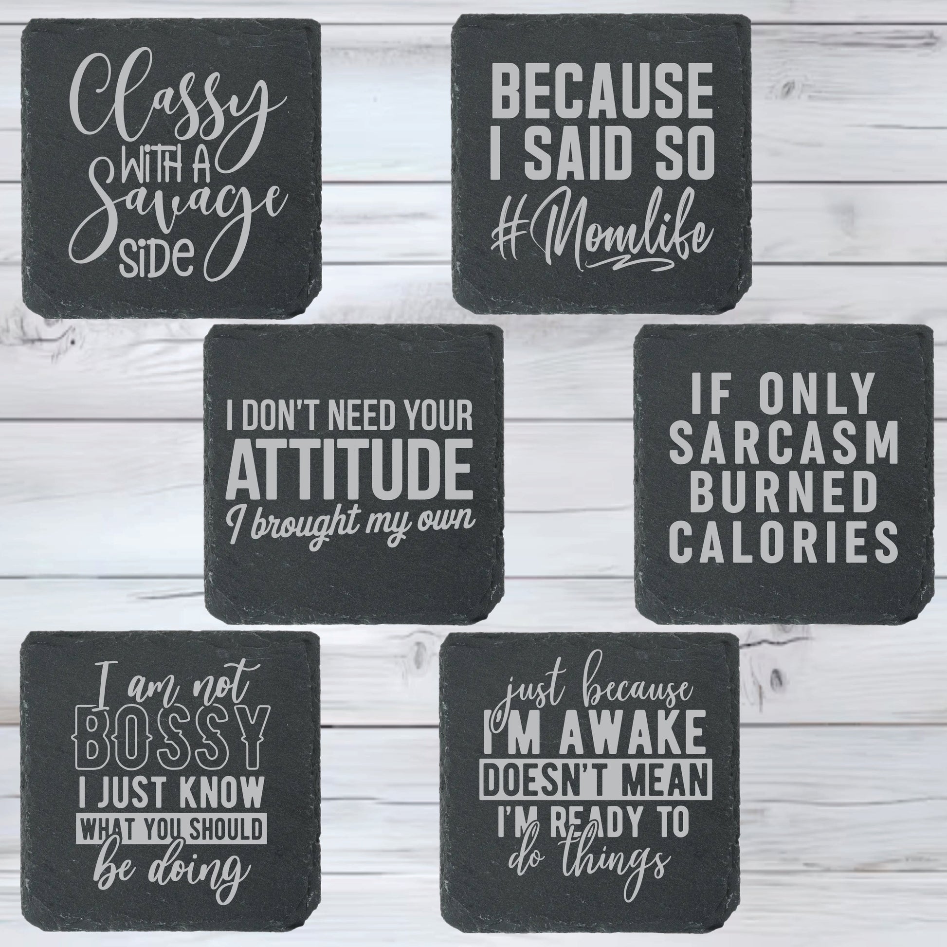 Set of black slate coasters with white text on a wooden surface